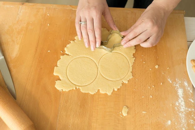 Mani femminili che tagliano pasta per biscotti