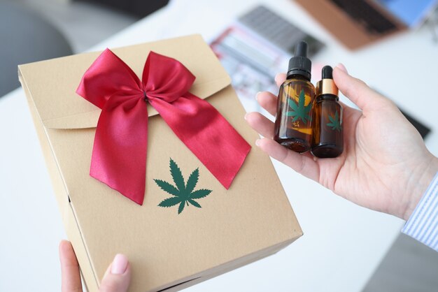 Mani femminili che tengono la carta da regalo con il primo piano di marijuana. Vendita legale del concetto di marijuana