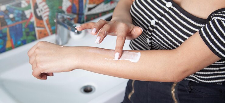 Mani femminili che tengono la crema per il corpo in bagno