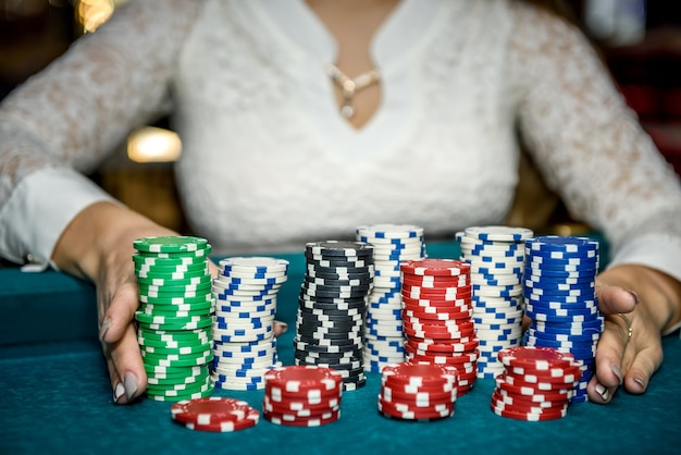 Mani femminili che tengono pile di fiches del casinò sul tavolo