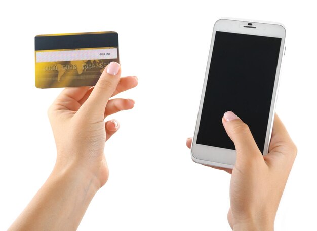 Mani femminili che tengono smartphone e carta di credito isolati su bianco