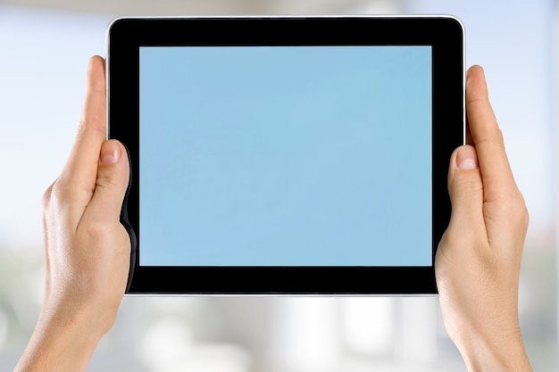 Mani femminili che tengono tablet digitale con schermo blu