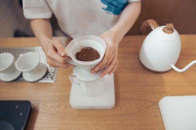 Mani femminili che tengono tazza di caffè con filtro di carta