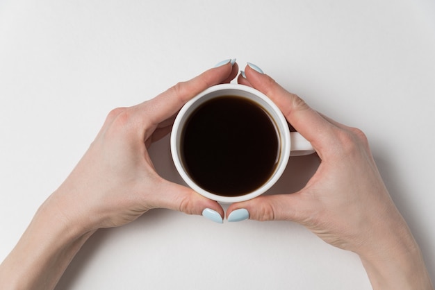 Mani femminili che tengono tazza di forte caffè sopra. Caffè del mattino.