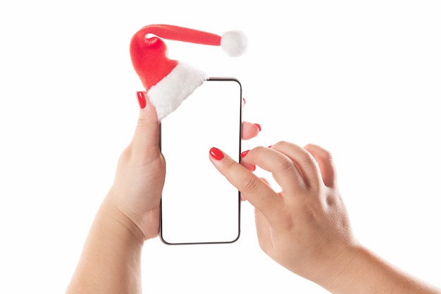 Mani femminili che tengono telefono astuto mobile con il cappello della Santa