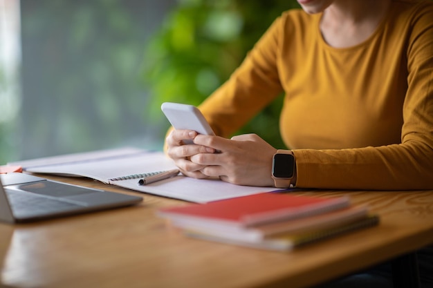 Mani femminili che tengono telefono nuovo di zecca che lavora al caffè