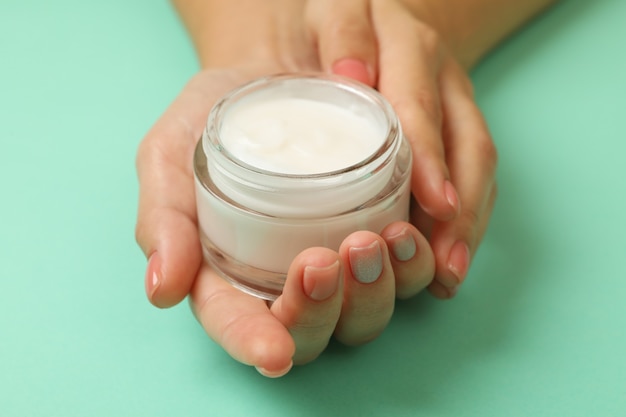 Mani femminili che tengono un barattolo di crema cosmetica