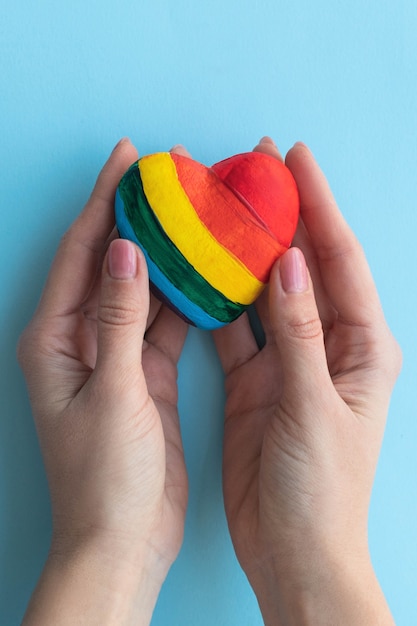 Mani femminili che tengono un cuore nei colori lgbt, concetto di amore libero.