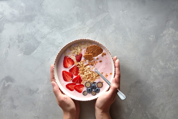 Mani femminili che tengono un piatto con una fresca colazione a base di yogurt