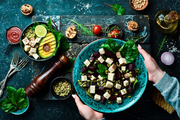 Mani femminili che tengono una ciotola di insalata di barbabietola tofu formaggio spinaci e semi di zucca Il concetto di mangiare sano Vista dall'alto