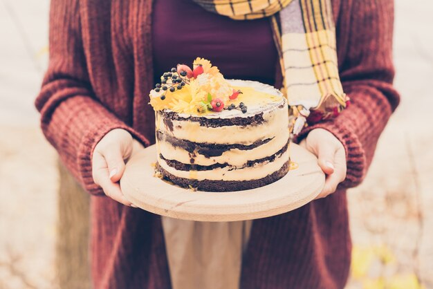 Mani femminili che tengono una torta marrone