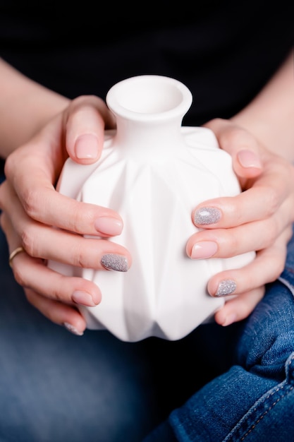 Mani femminili che tengono vaso in ceramica bianca Manicure con smalto rosa e grigio