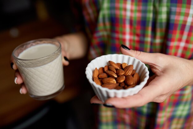 Mani femminili con bicchiere di latte di mandorla vegano Tipi alternativi di latti non caseari Latte vegetale di vari grani Mangiare pulito Dieta sanaxA