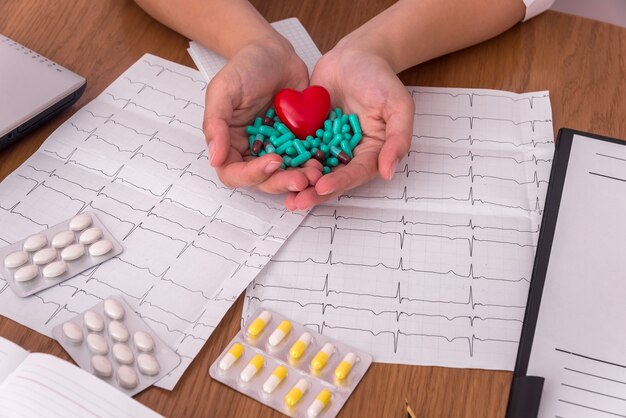 Mani femminili con capsule verdi e cuore rosso