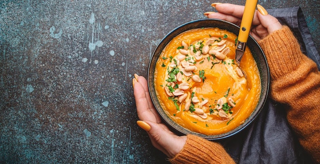 Mani femminili con ciotola di zuppa di zucca