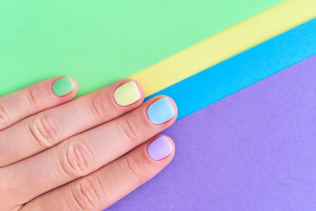 Mani femminili con colori vivaci su uno sfondo colorato