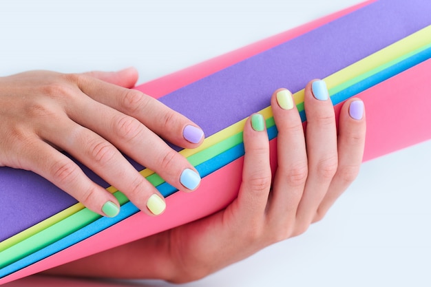 Mani femminili con colori vivaci su uno sfondo colorato