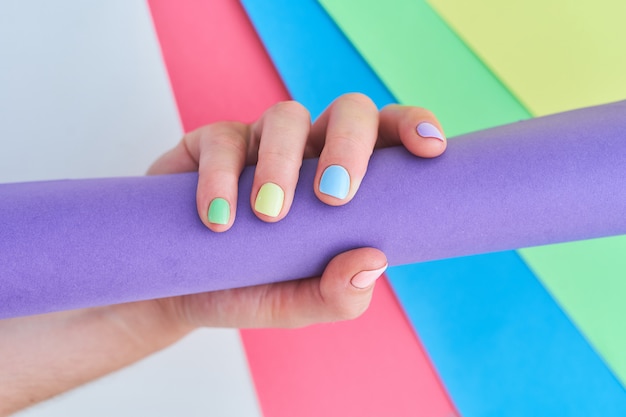 Mani femminili con colori vivaci su uno sfondo colorato