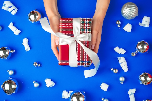 Mani femminili con confezione regalo su sfondo blu