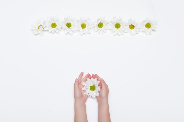 Mani femminili con crema e bellissimi fiori su sfondo chiaro