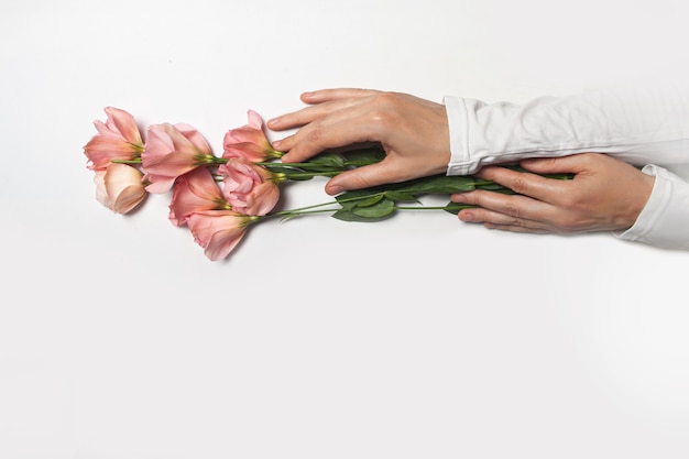 Mani femminili con fiori di eustoma su sfondo bianco.