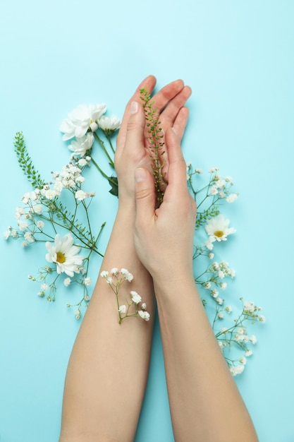 Mani femminili con fiori su sfondo blu