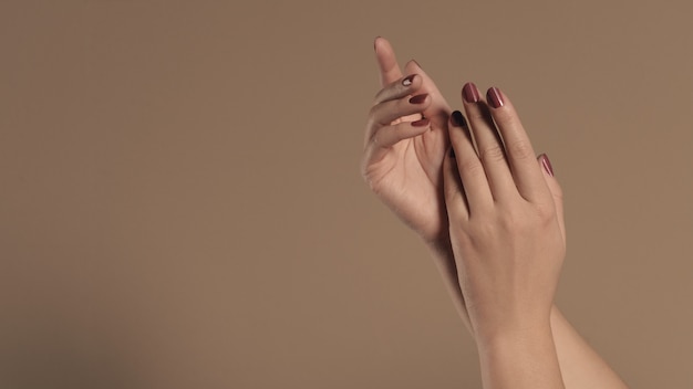 Mani femminili con i chiodi rossi dipinti su fondo beige