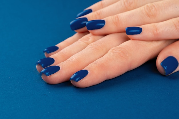 Mani femminili con manicure di classico colore blu. Avvicinamento