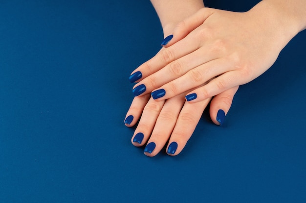 Mani femminili con manicure di classico colore blu. Avvicinamento