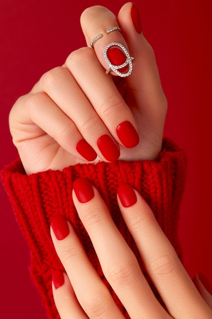 Mani femminili con manicure in maglione rosso opaco design delle unghie