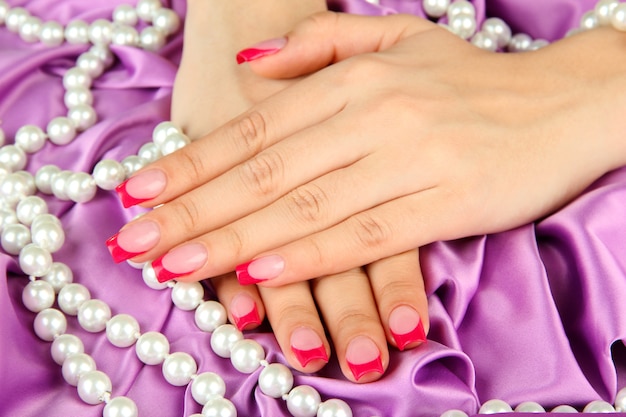 Mani femminili con manicure rosa su gioielli