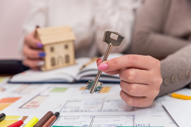 Mani femminili con modello di casa in legno e chiave