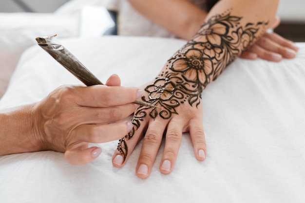 Mani femminili con motivo mehendi di fiori artista che dipinge con l'henné