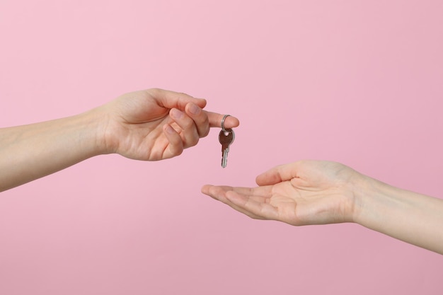 Mani femminili con una chiave su uno sfondo rosa