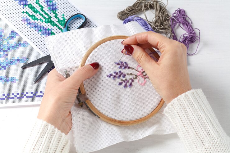 Mani femminili con una croce ricamata sui motivi floreali dei tessuti