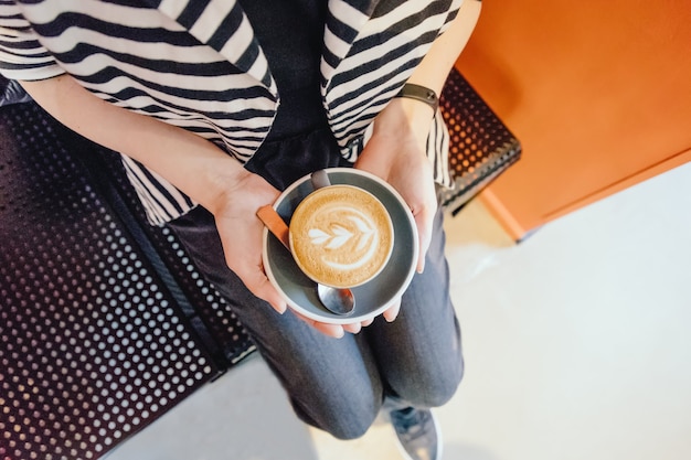 Mani femminili con una tazza di caffè cappuccino