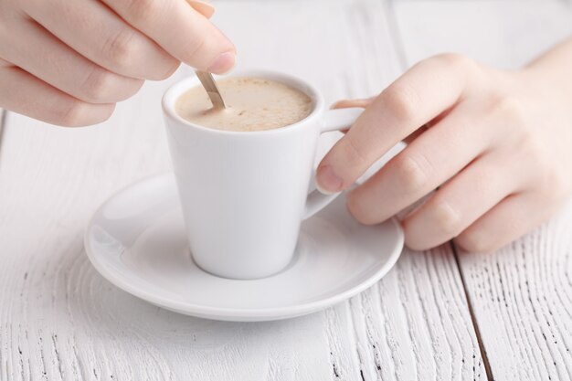 Mani femminili con una tazza di cappuccino in un caffè