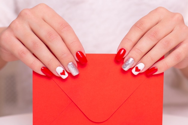 Mani femminili con unghie rosse manicure, disegno cuori