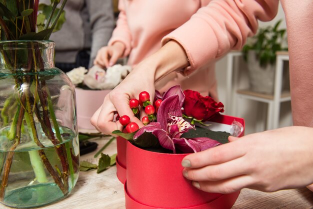 Mani femminili del fiorista che organizzano composizione floreale