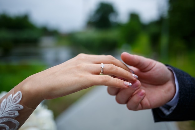 Mani femminili delicate della sposa con un anello nuziale d'oro sull'anulare