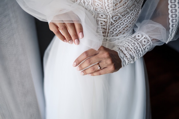 Mani femminili delicate della sposa con un anello nuziale d'oro sull'anulare