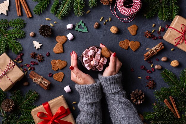 Mani femminili di Natale con scatole regalo e tazza di cacao