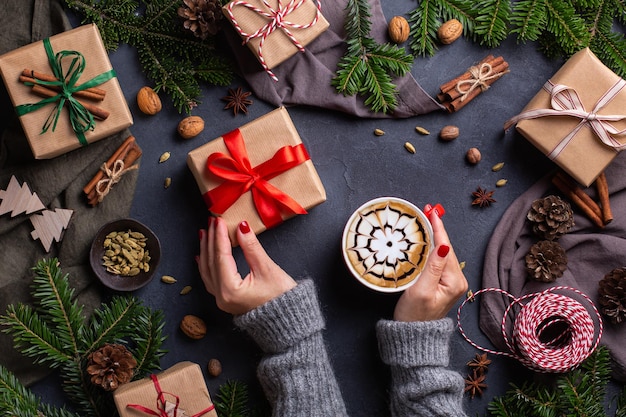 Mani femminili di Natale con scatole regalo e tazza di caffè