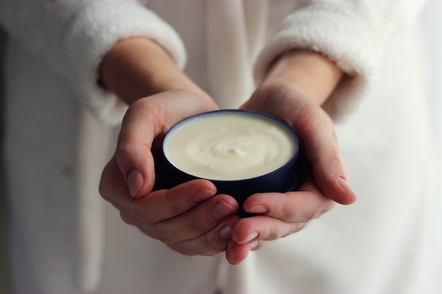 Mani femminili e barattolo di crema closeup con posto per testo