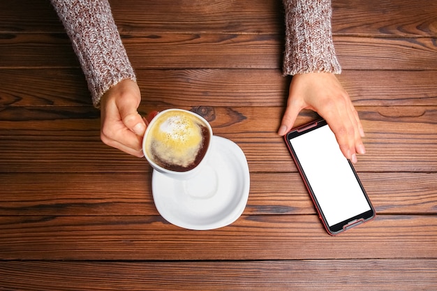 Mani femminili e caffè su fondo in legno