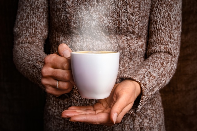 Mani femminili e caffè su fondo in legno