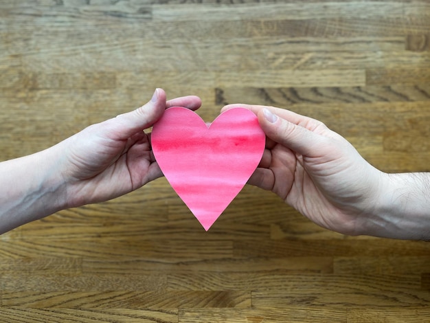 Mani femminili e maschili che tengono un cuore rosso San Valentino amore romantico o contenuto relativo al matrimonio