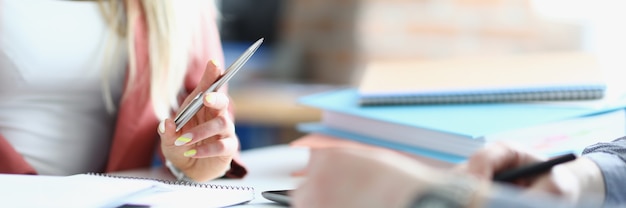 Mani femminili e maschili con penne con quaderni sul tavolo di lavoro