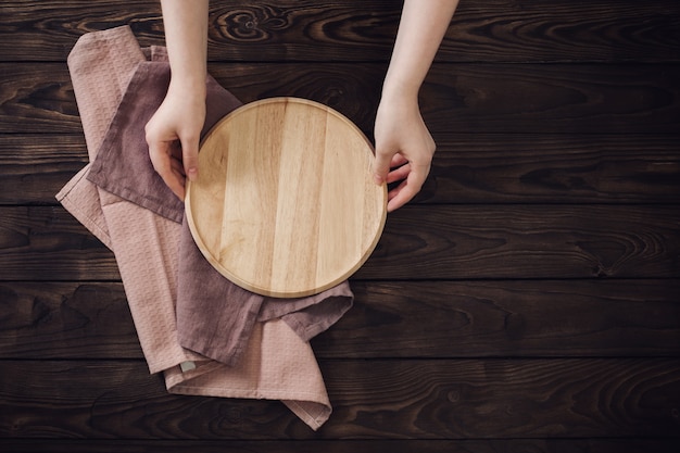 Mani femminili e piatti di legno sulla vecchia tavola di legno