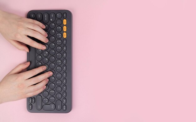 Mani femminili e tastiera su sfondo rosa Concetto di lavoro nell'area di lavoro presso il computer di casa e design freelance Vista dall'alto piatta e spazio di copia foto